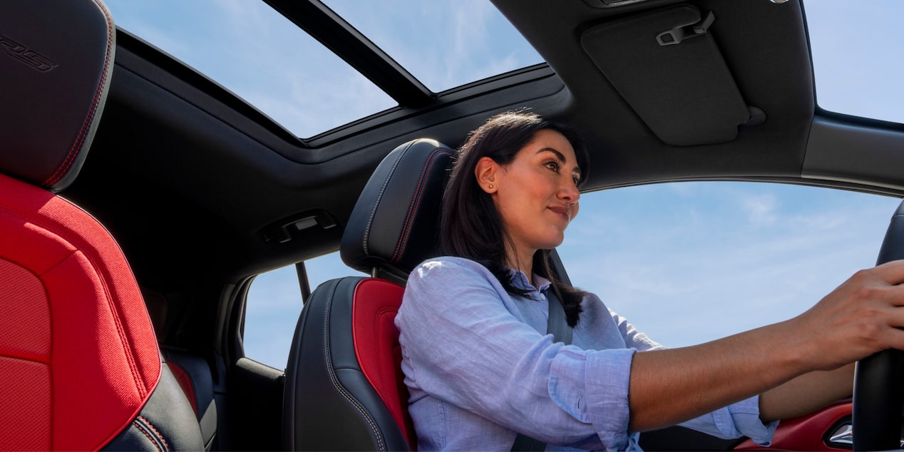 Side View of a Woman Driving a 2025 Chevy Equinox EV under a Blue Sky