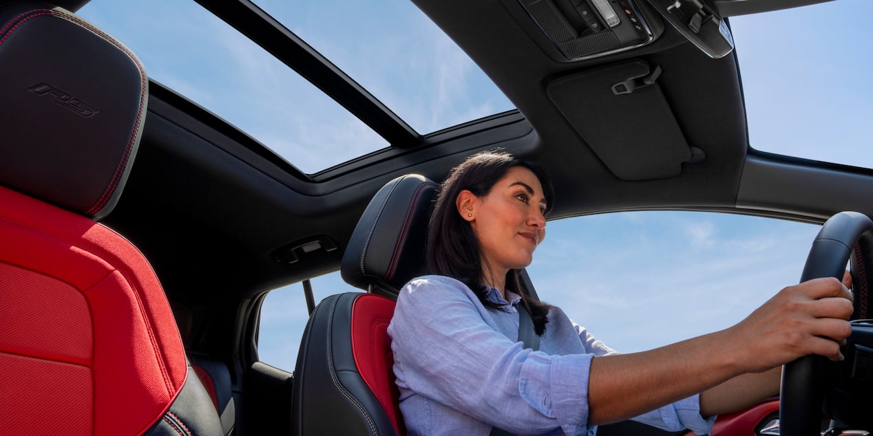 Side View of a Woman Driving a 2025 Chevy Equinox EV under a Blue Sky