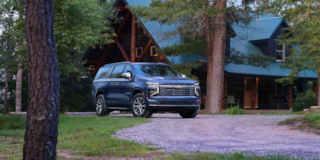 Front Three-Quarters View of the 2025 Chevrolet Suburban SUV Parked in Front of a Cabin