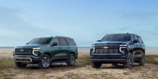 A Three-quarters View of a 2025 Chevrolet Suburban and 2025 Tahoe Parked near the Lake