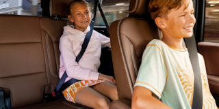 Two Kids Smiling While Seated in the Second Row and Third Row of the 2025 Chevrolet Suburban