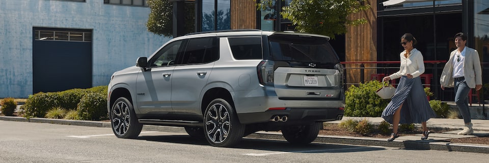 Una pareja camina hacia su Chevy Tahoe 2025 estacionada frente a una tienda