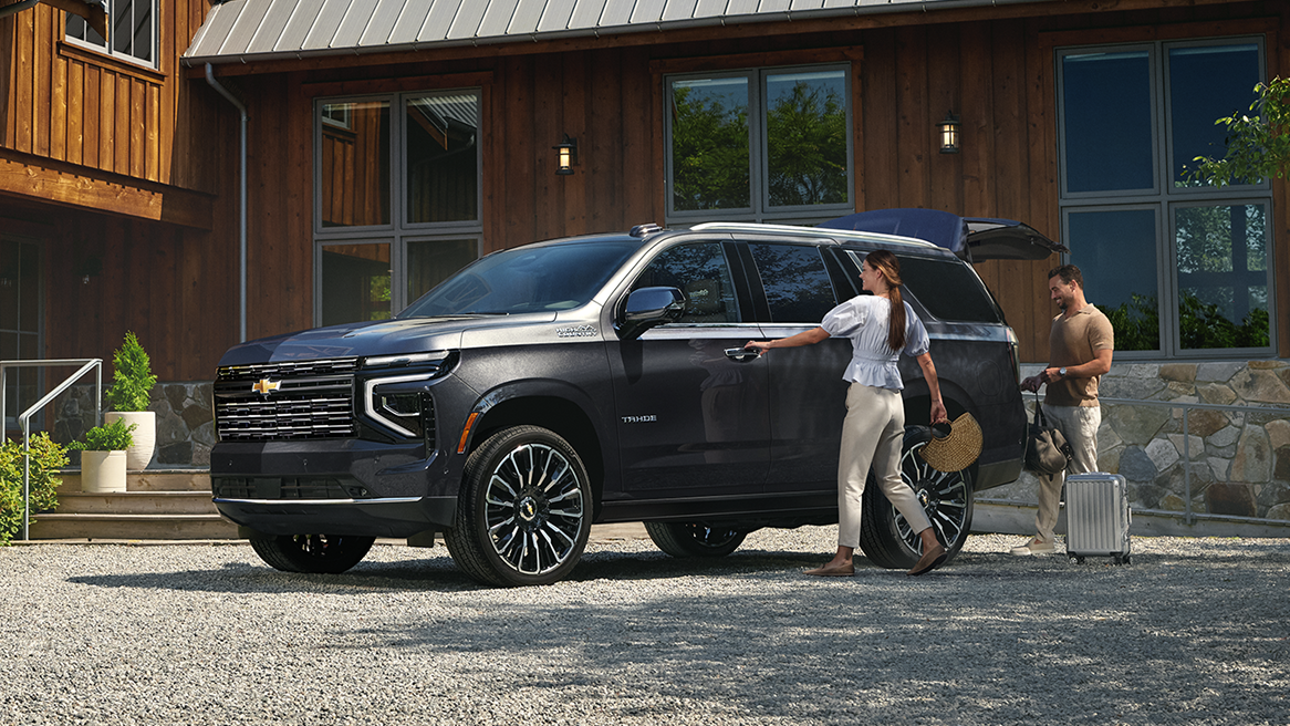 Una pareja carga equipaje en la cajuela de su Chevy Tahoe 2025