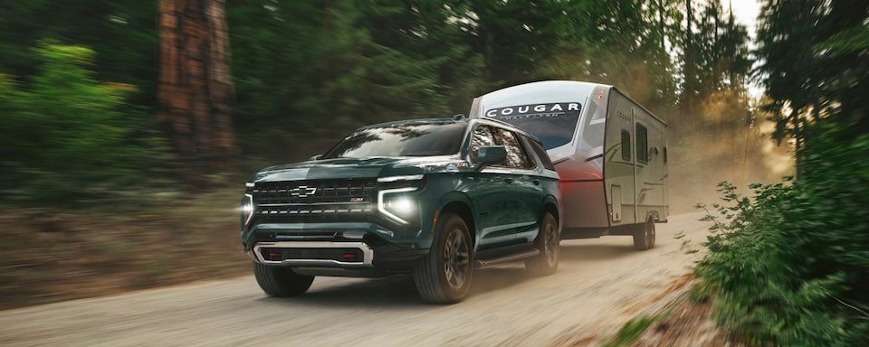 Una Chevy Tahoe 2025 remolcando una casa rodante en el bosque