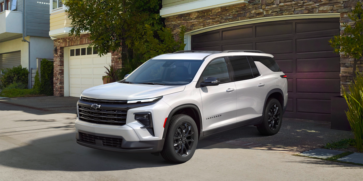 Three Quarters View of a 2025 White Chevy Traverse Coming Out of a Garage