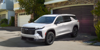 Three Quarters View of a 2025 White Chevy Traverse Coming Out of a Garage