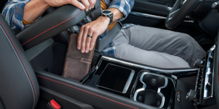 A Man Putting His Wallet in the Arm Resting Compartment of the 2025 Chevy Traverse