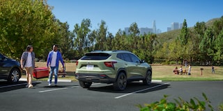 Two Men Walking Toward Their Parked 2025 Chevy Trax in a Parking Lot