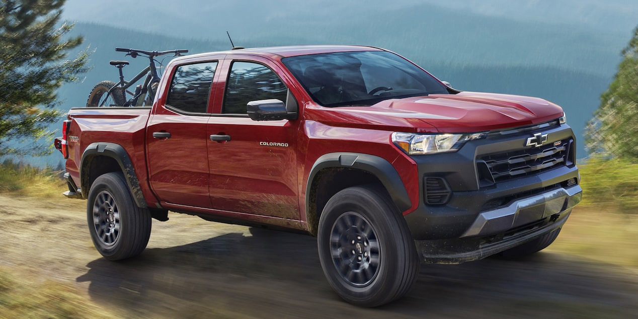Three Quarters View of a 2025 Red Chevy Colorado at a High Altitude with Mountains Seen at a Distance