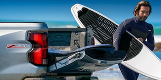 A Man in a Wet Suit Unloads His Kayak from his Chevy Colorado