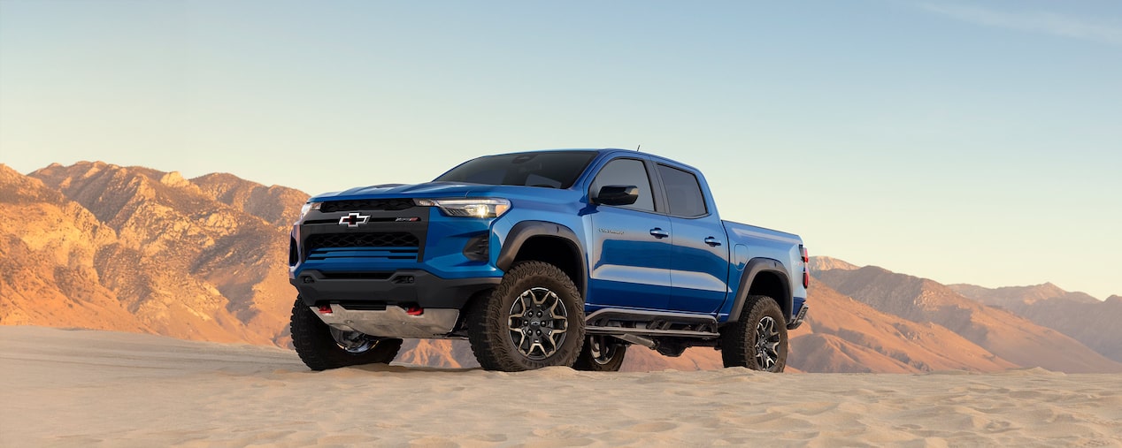 Three Quarters View of a Blue Chevy Colorado on a Rocky Plane Next to a Hill