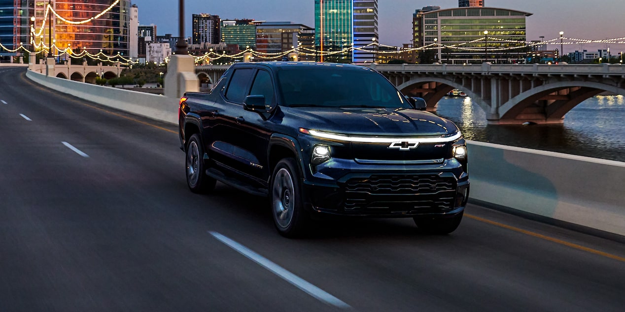 Three quarter view of a black 2025 Silverado EV a road in the evening