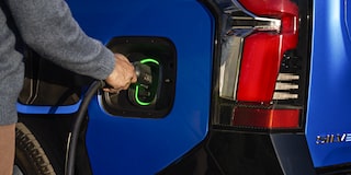 A person plugging in a charger to a 2025 blue Chevy Silverado EV
