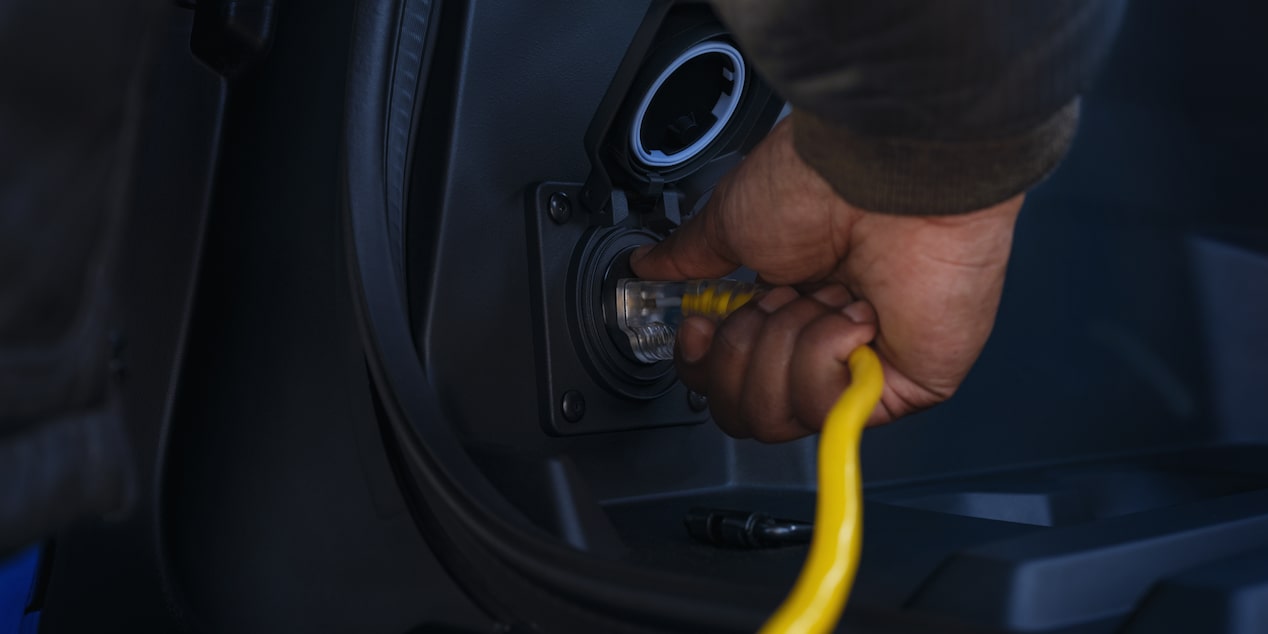 A person inserting a charging port in the 2025 Chevy Silverado EV