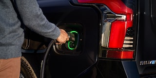 A person plugging in a charger to a 2025 black Chevy Silverado EV