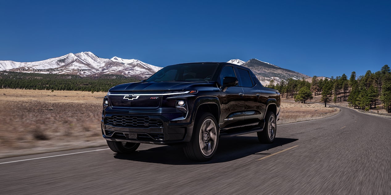 Three quarters view of a 2025 black Chevy Silverado EV with mountains in the distance