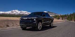 Three quarters view of a 2025 black Chevy Silverado EV with mountains in the distance