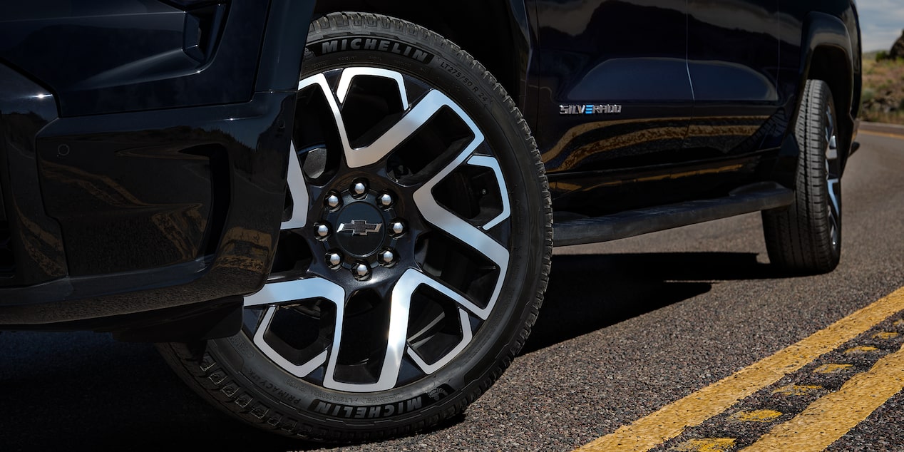 Low angle view of the tires of a black 2025 Chevy Silverado EV on a road