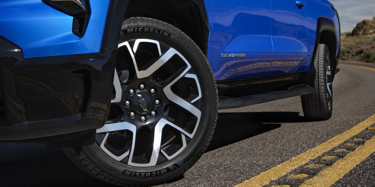 Low angle view of the tires of a blue 2025 Chevy Silverado EV on a road