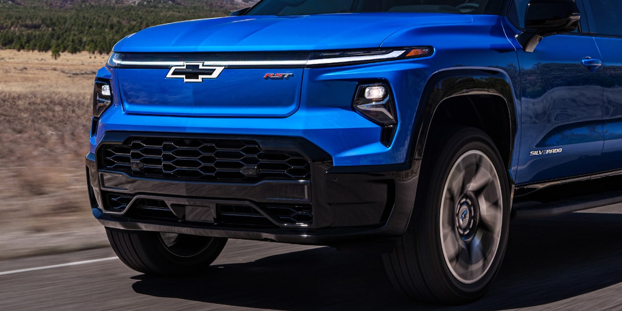 Front close-up of a blue Chevy 2025 Silverado EV driving down the road
