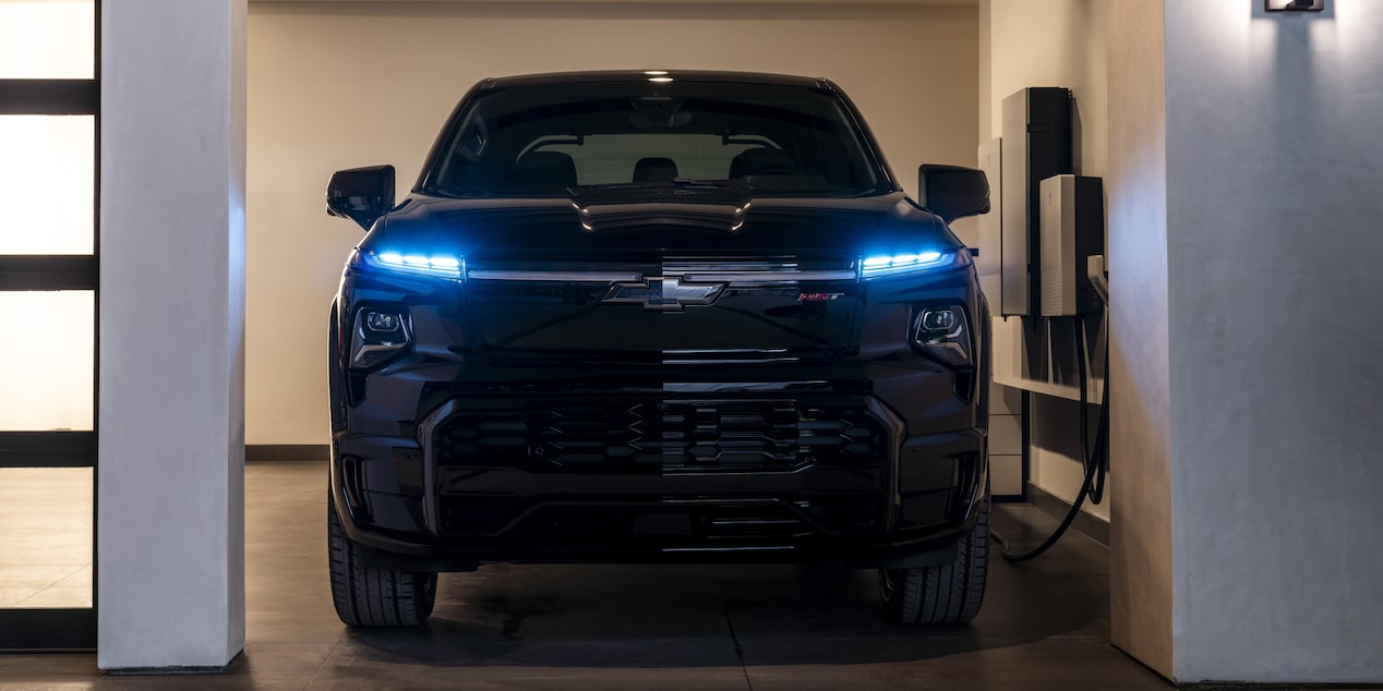Front view of a black 2025 Chevy Silverado EV in a garage at night