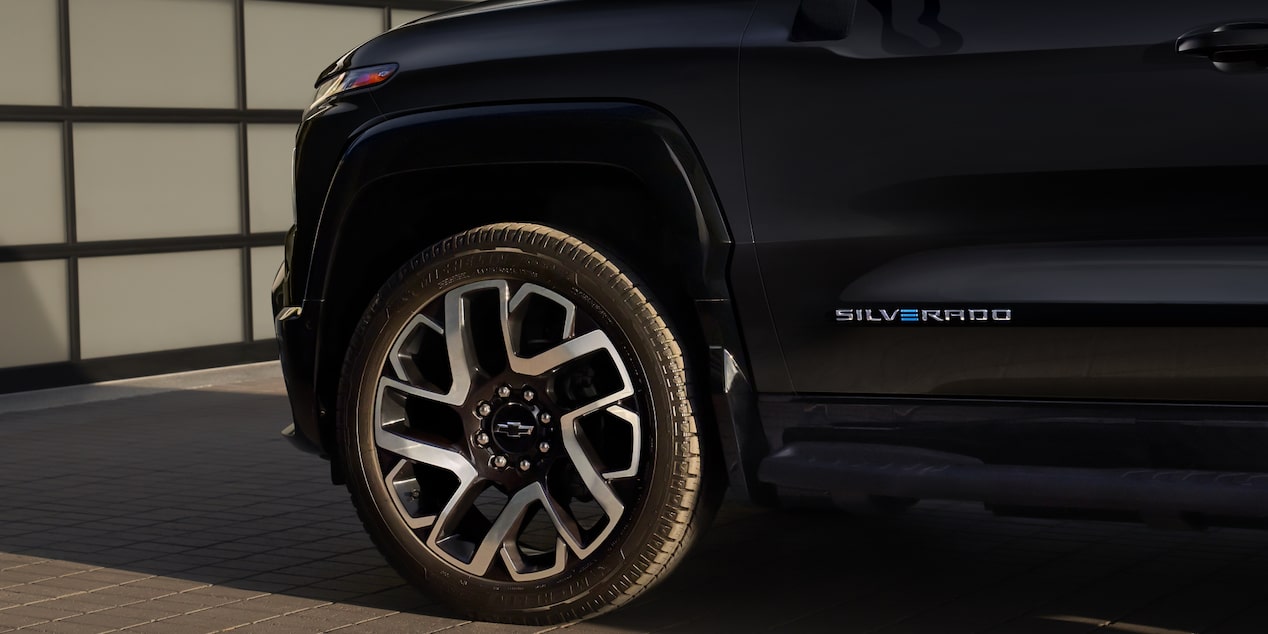 Close-view of the side of a black 2025 Chevy Silverado EV in front of a garage 