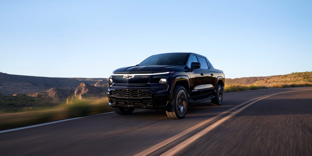 Three quarters view of a 2025 black Chevy Silverado EV going down the road