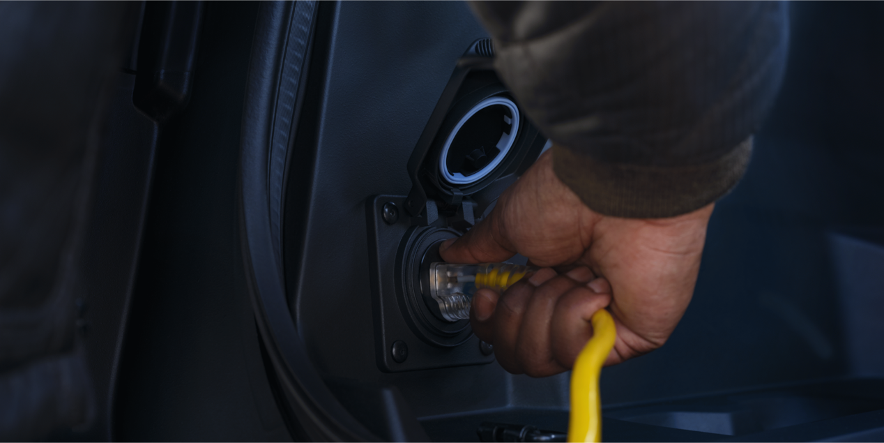 A person plugging in a power cord into a 2025 Chevy Silverado EV