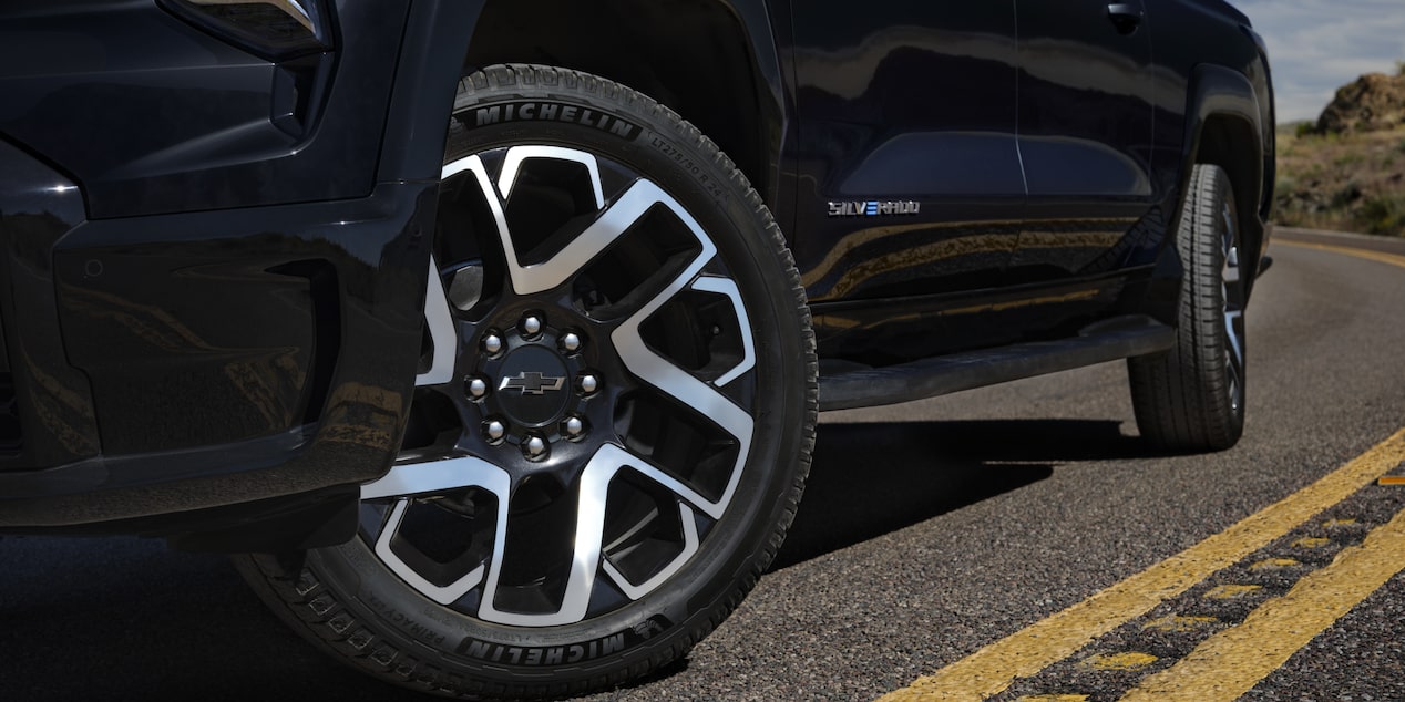 Low angle view of the tires of a black 2025 Chevy Silverado EV on a road
