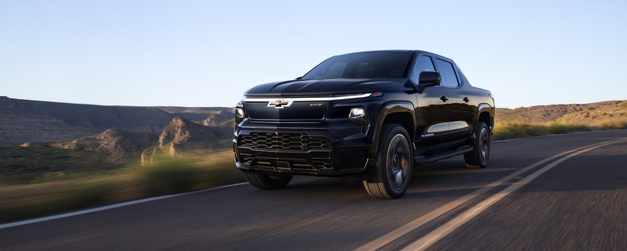 Three quarters view of a 2025 black Chevy Silverado EV going down the road
