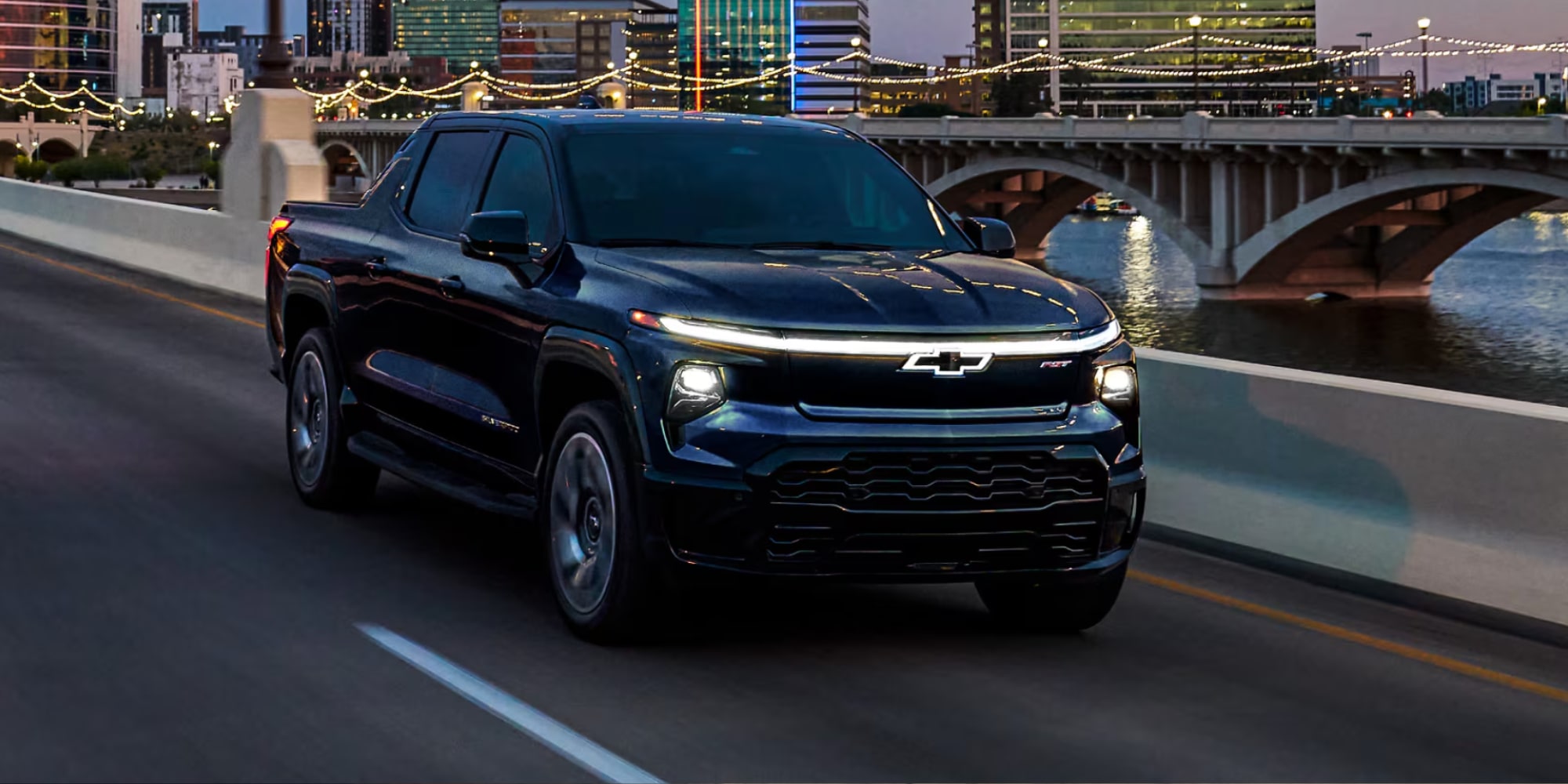 Passenger Side Profile View of a Black Silverado EV Driving at Dusk
