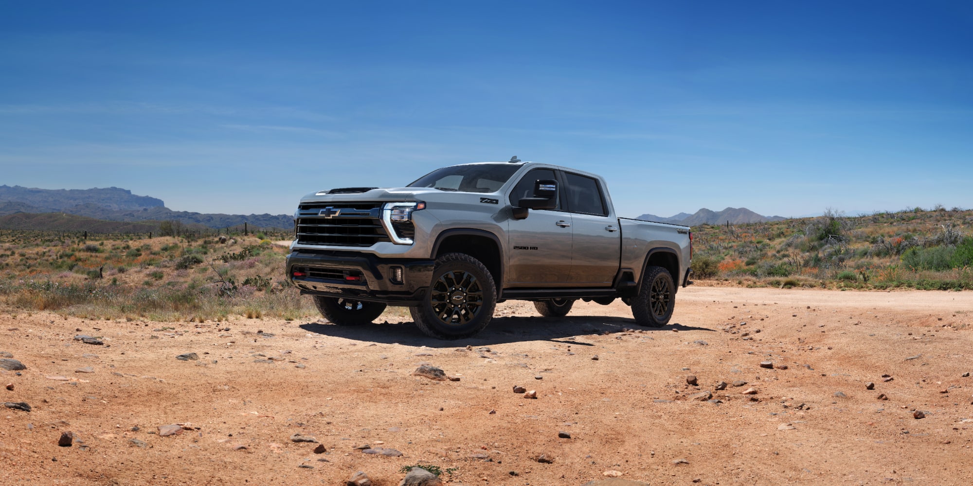 "A powerful Chevrolet Silverado 2500 stands parked on open ground, showcasing its rugged design and robust presence