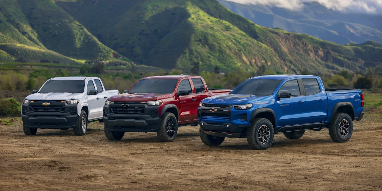 Chevrolet Colorado Trucks Parked on a Dirt Plane Next to Grass Mountains