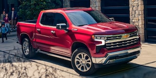Three Quarters View of a Red 2025 Chevy Silverado Pickup Truck Parked Next to a Building
