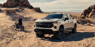 A Three Quarters View of a White Silverado Next to a Motorcycle on a Desert