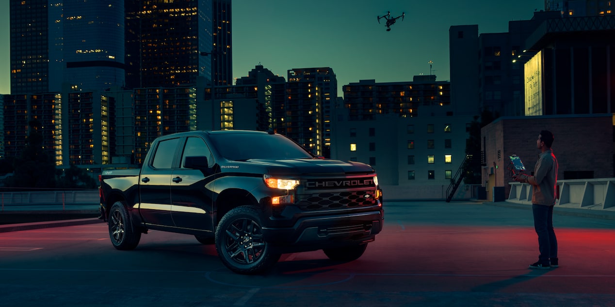 Three Quarters View of 2025 Chevy Silverado Pickup Truck at Night and a Man Infront