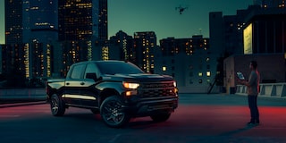 Three Quarters View of 2025 Chevy Silverado Pickup Truck at Night and a Man Infront