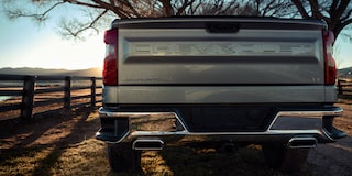 A Black 2025 Chevy Silverado Pickup Truck Pulling a Trailer with Sunlight from the Back