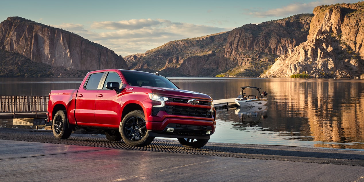 Side View of a Red 2025 Chevy Silverado Pickup Truck Next to a Beautiful Lake