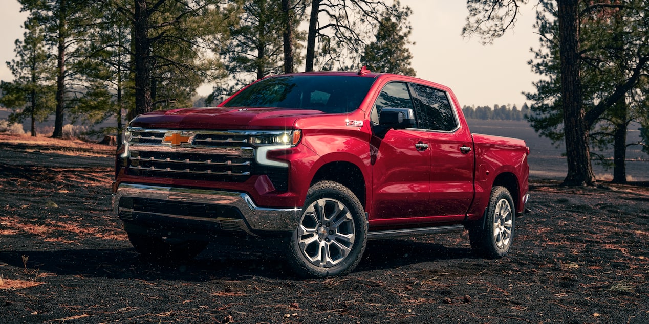 Three Quarters View of a Red 2025 Chevy Silverado Pickup Truck Surrounded by Trees