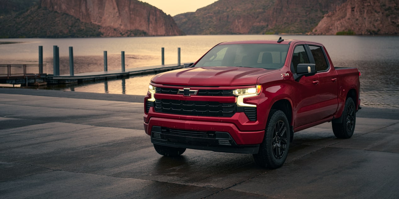 A Three Quarters View of a Red 2025 Chevy Silverado Pickup Truck Next to a Lake