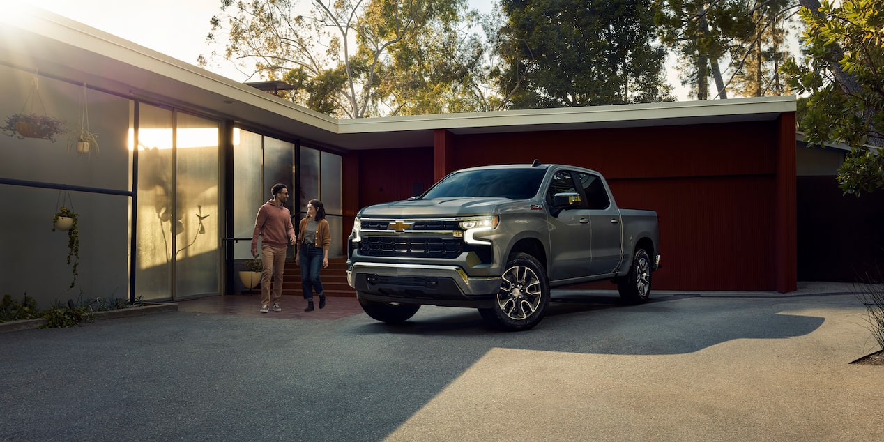 A Chevy Silverado Pickup Truck Next to a House and a Couple