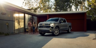 A Chevy Silverado Pickup Truck Next to a House and a Couple