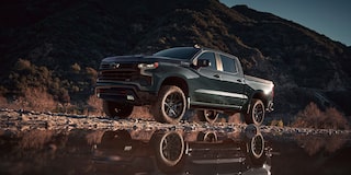 Three Quarters View of a Cypress Gray Chevy Silverado Pickup Truck next to a puddle in front of a mountain