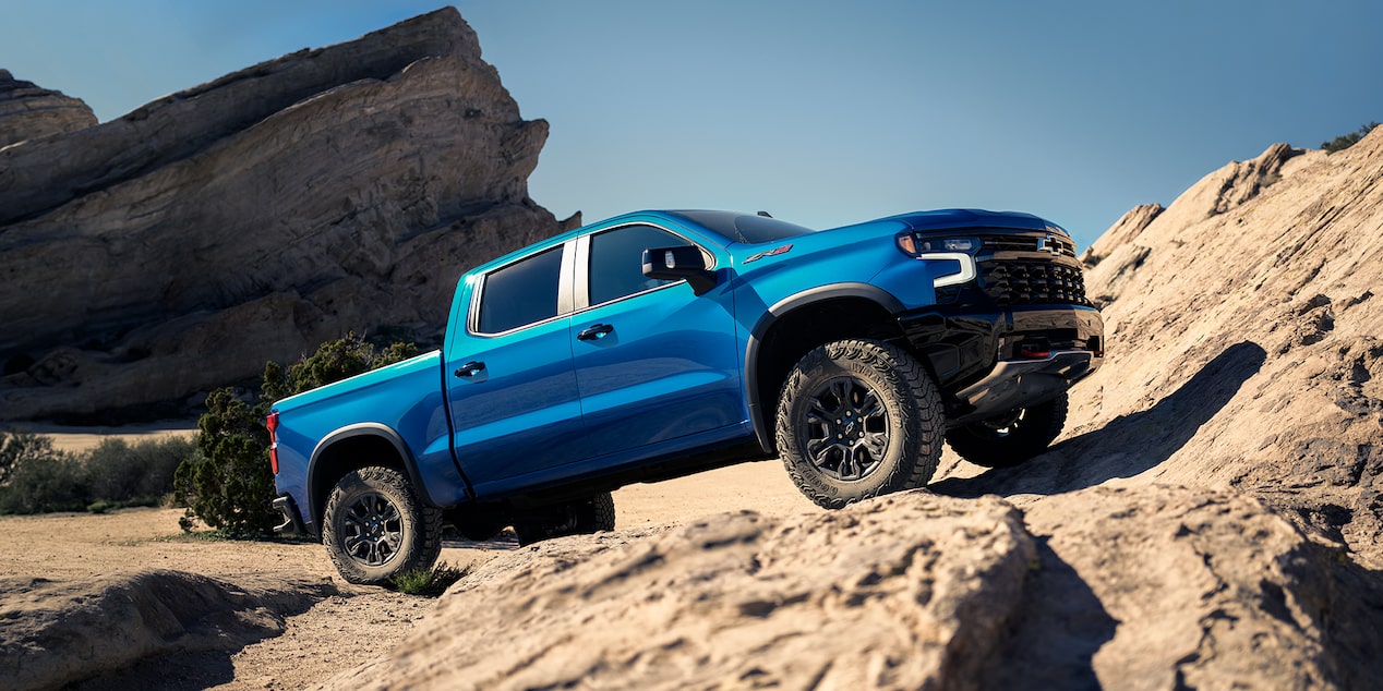 Side View of a Blue 2025 Chevy Silverado Going up a Rocky Plain