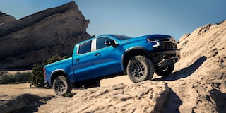 Side View of a Blue 2025 Chevy Silverado Going up a Rocky Plain