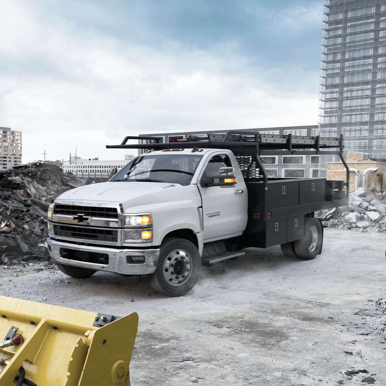 La Chevy Silverado de carga media y chasis con cabina 2026 estacionada en una obra en construcción con montones de piedra cerca