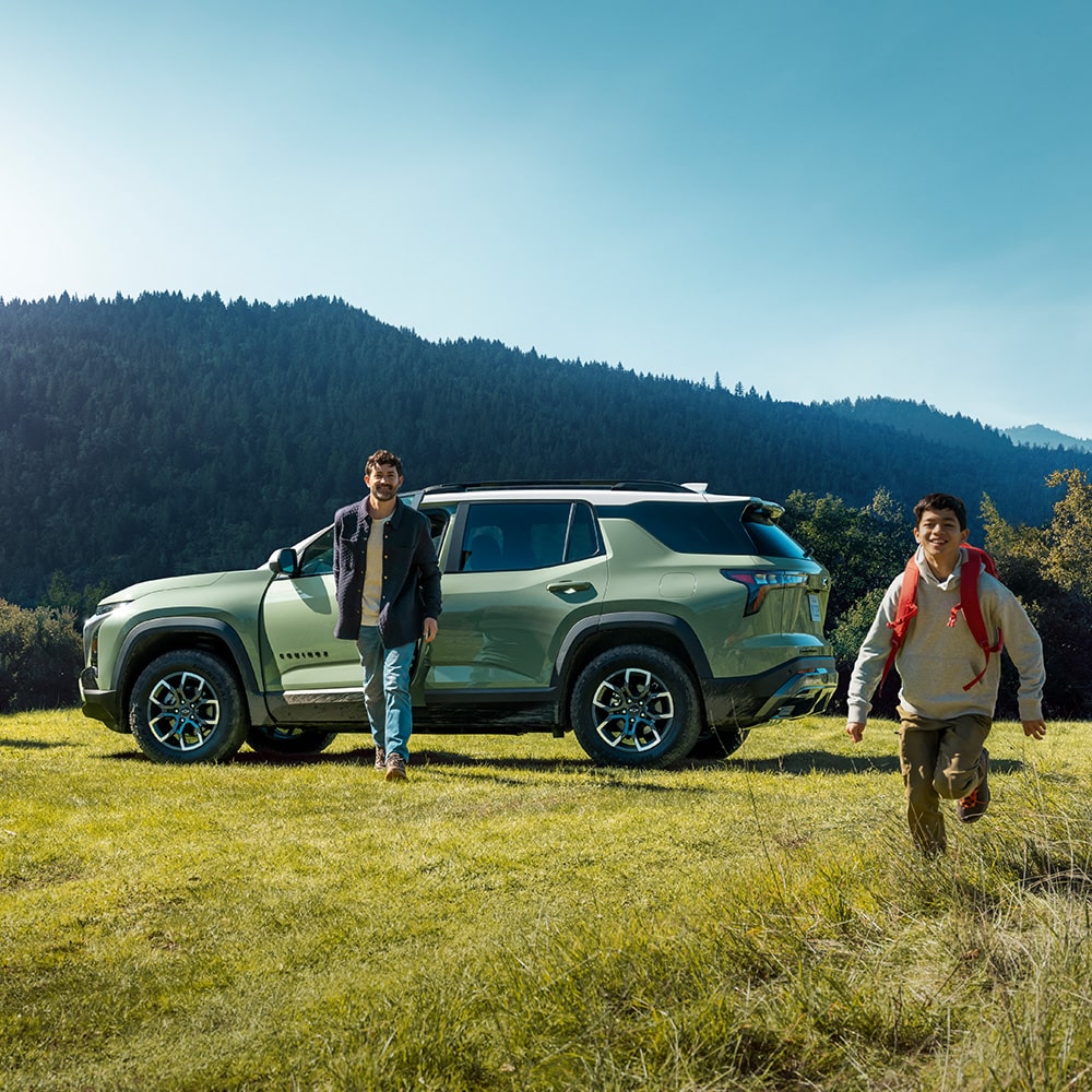 A Father and His Son Walking Away From Their Parked 2026 Chevy Equinox in the Woods