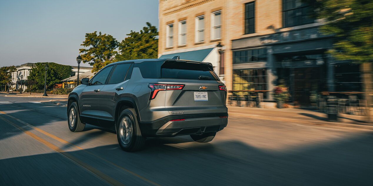 Rear Exterior View of the 2026 Chevy Equinox Driving Through a Downtown