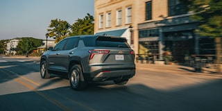 Rear Exterior View of the 2026 Chevy Equinox Driving Through a Downtown
